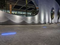 a street scene with focus on a circular wall and lights at night time, looking like they could fly