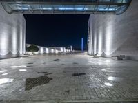 the lights are dimmed on a large walkway outside of a building at night time