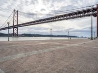 a tall metal suspension bridge across a body of water with a lot of traffic below it