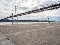 a tall metal suspension bridge across a body of water with a lot of traffic below it