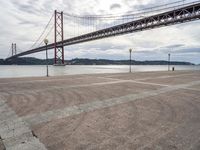 a tall metal suspension bridge across a body of water with a lot of traffic below it