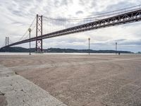 a tall metal suspension bridge across a body of water with a lot of traffic below it