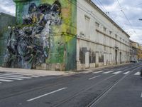 a painting on a green wall by a busy street and train tracks in the city