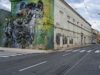 a painting on a green wall by a busy street and train tracks in the city