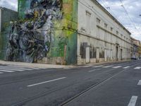 a painting on a green wall by a busy street and train tracks in the city