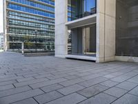 an empty concrete sidewalk in front of an apartment building with glass doors on both sides