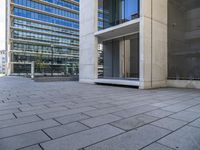 an empty concrete sidewalk in front of an apartment building with glass doors on both sides