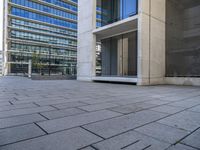 an empty concrete sidewalk in front of an apartment building with glass doors on both sides