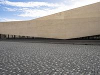 a large rectangular building sitting on the side of a road under a partly cloudy sky