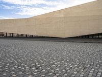 a large rectangular building sitting on the side of a road under a partly cloudy sky