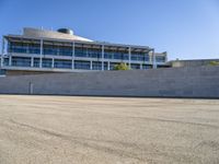 a building next to a road that is empty and has concrete bricks and grey steps