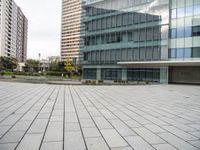 a square pavement in the middle of an empty building near a row of tall buildings