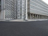 a concrete building with columns next to it and an empty street below them on an overcast day