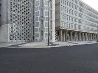 a concrete building with columns next to it and an empty street below them on an overcast day