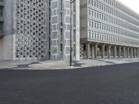 a concrete building with columns next to it and an empty street below them on an overcast day