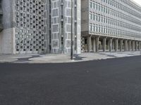 a concrete building with columns next to it and an empty street below them on an overcast day