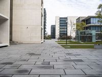 there is a sidewalk with lots of blocks in it between tall buildings and trees in the background