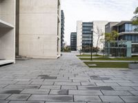 there is a sidewalk with lots of blocks in it between tall buildings and trees in the background