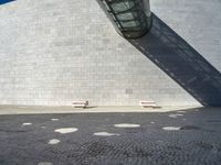 there are four small white benches in front of the building by the door and on the pavement