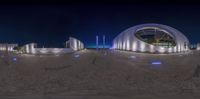 a panorama photo of buildings in the night, lit up by lights, against a dark blue sky