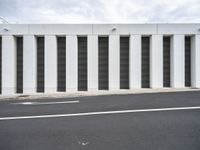 an empty street with no traffic in the distance next to a wall with striped shutter