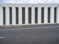 an empty street with no traffic in the distance next to a wall with striped shutter