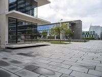 a view of a courtyard with a stone floor and glass walls from the building's side