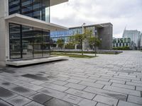 a view of a courtyard with a stone floor and glass walls from the building's side