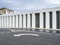 the empty parking lot has two road signs on it's sides and white columns