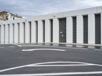 the empty parking lot has two road signs on it's sides and white columns