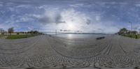 a fisheye image of the sun in the sky over the water and a river in the background