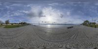 a fisheye image of the sun in the sky over the water and a river in the background