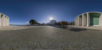 a circular panorama of a sidewalk near some stone buildings on a clear day with the sun in the distance