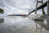 a skate park with ramps at the bottom and some graffiti in the background near a large bridge