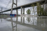 a skate park under a bridge with graffiti on it's wall and in the ground is a river