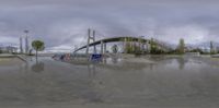 an empty skateboard park with multiple ramps and bridges above water level with clouds in the sky