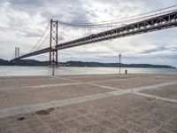 a view of a large bridge on a cloudy day with water and buildings in the distance