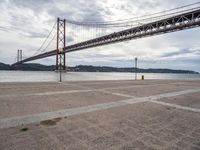 a view of a large bridge on a cloudy day with water and buildings in the distance