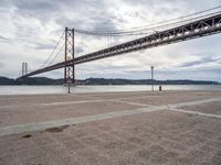 a view of a large bridge on a cloudy day with water and buildings in the distance