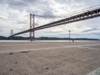 a view of a large bridge on a cloudy day with water and buildings in the distance