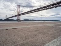 a view of a large bridge on a cloudy day with water and buildings in the distance