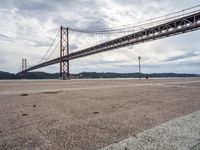 a view of a large bridge on a cloudy day with water and buildings in the distance