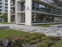 an office building with windows on all sides and green grass around it and some benches