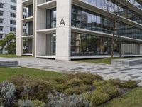 an office building with windows on all sides and green grass around it and some benches