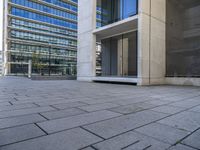 a large building that has lots of windows and stone pavement near it's outside