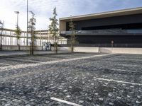 a parking area with a walkway and some trees in front of it with several windows