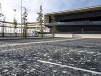 a parking area with a walkway and some trees in front of it with several windows