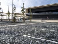 a parking area with a walkway and some trees in front of it with several windows