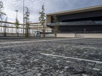 a parking area with a walkway and some trees in front of it with several windows