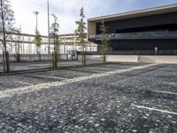 a parking area with a walkway and some trees in front of it with several windows